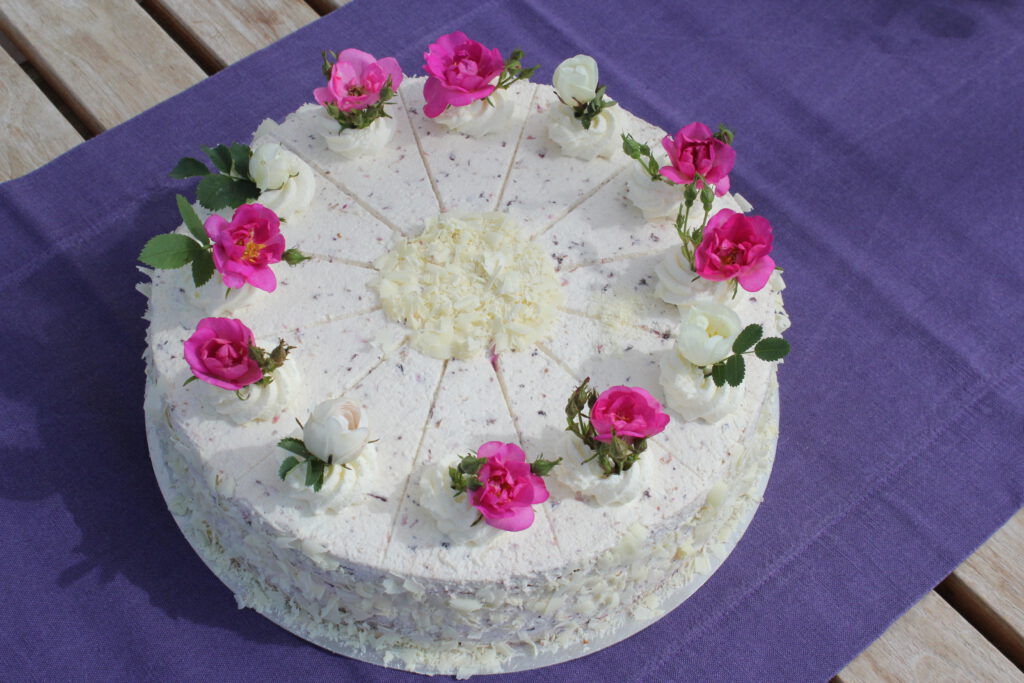Torte mit weißer Creme, verziert mit rosa Rosenblüten