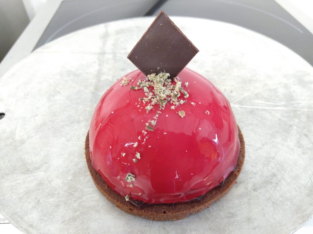 Rot glasiertes Kuppeltörtchen mit einem Schokoladenplättchen