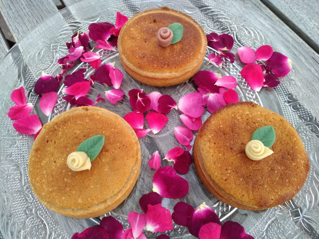 Marzipan-Rosen-Tartes mit kleiner Marzipanrose, umgeben von Rosenblättern
